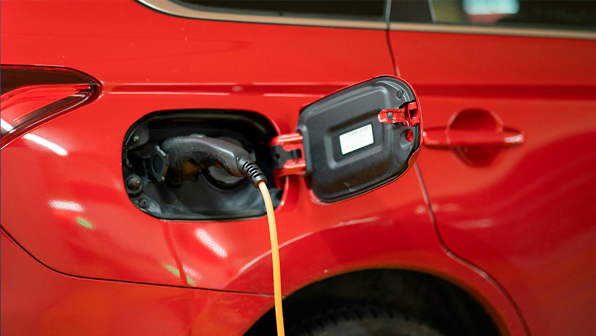 Electromovilidad: baterias sostenibles. Coche eléctrico rojo recargando la batería.